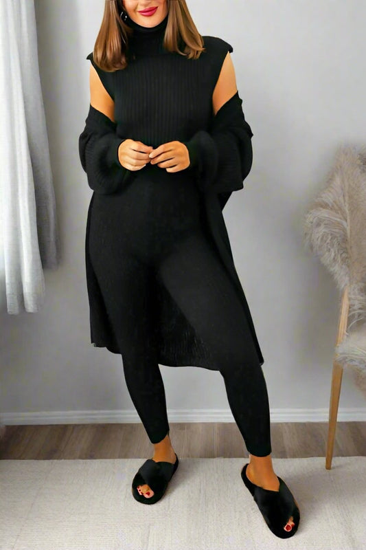 Woman wearing a black outfit with cut-out shoulders in a room.